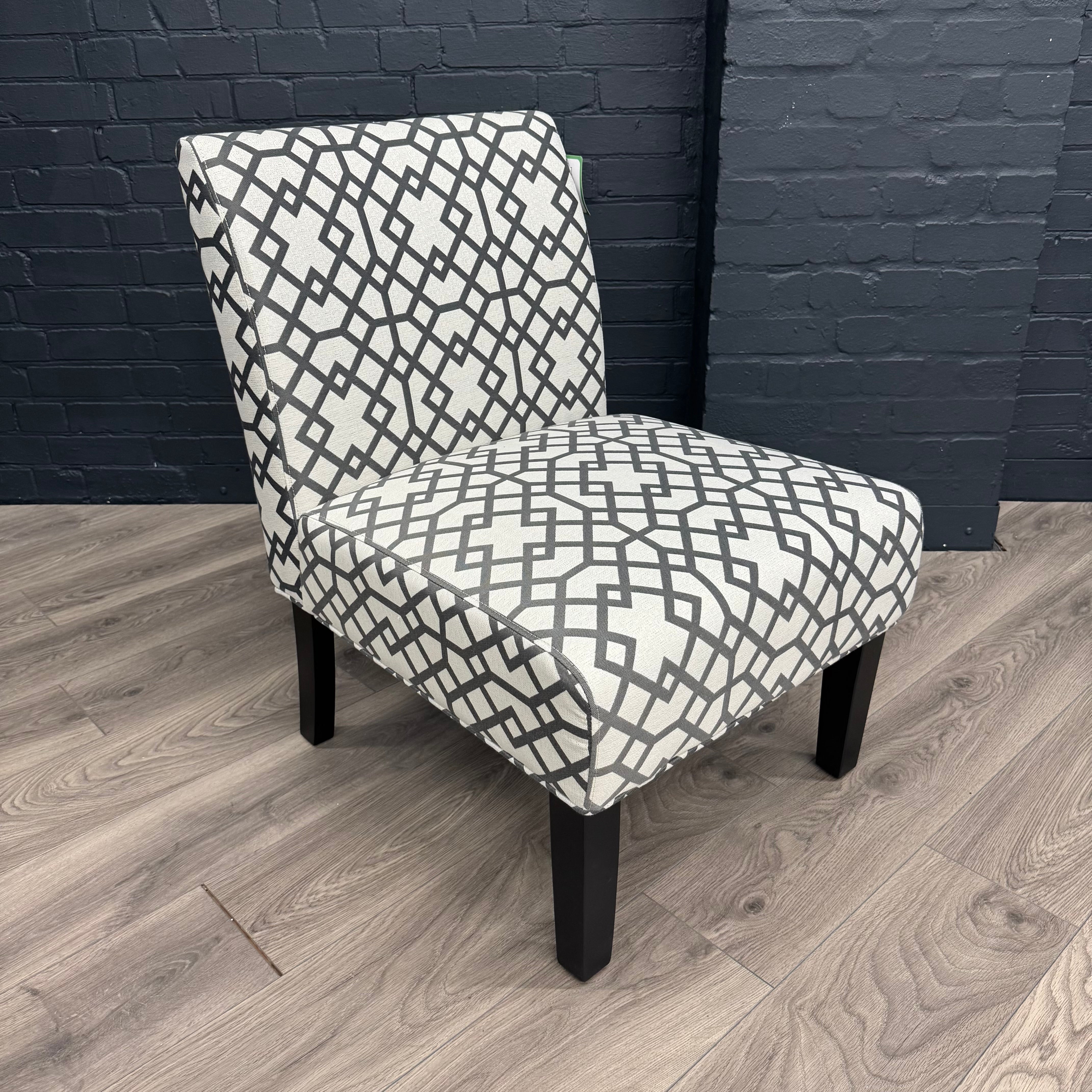 Chair with geometric patterned fabric against a dark brick wall.