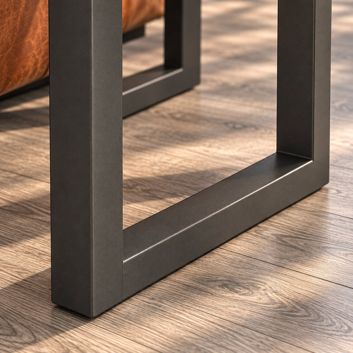 Detail of the Fusion oak lamp table's charcoal loop frame, with straight uprights and a floor-level connecting bar.
