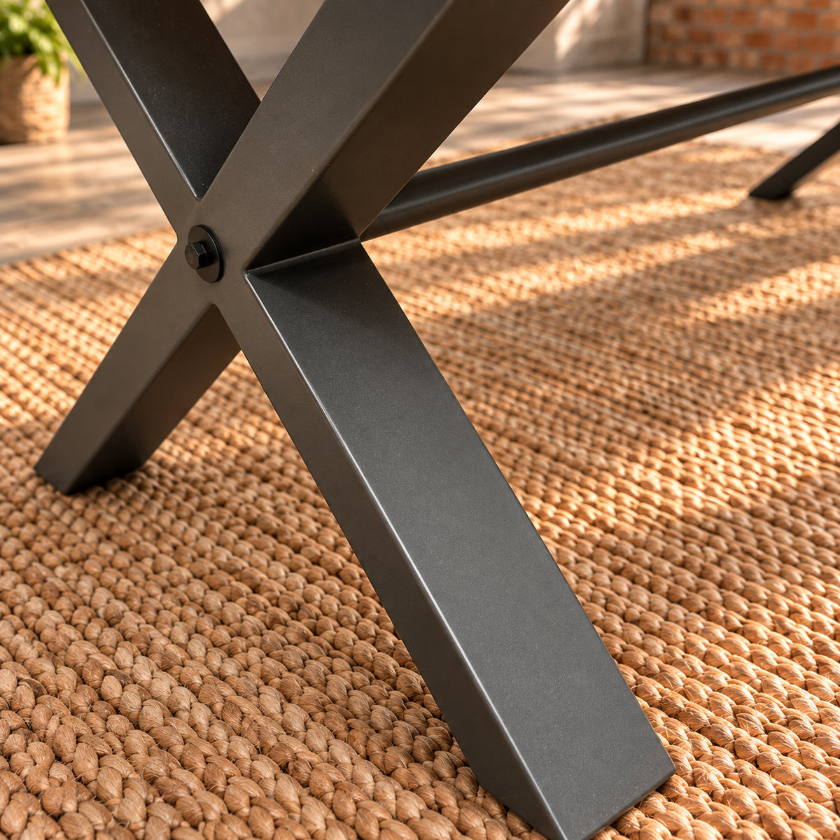 Detail of the Fusion oak large dining table’s charcoal metal cross leg and foot on a natural woven rug.
