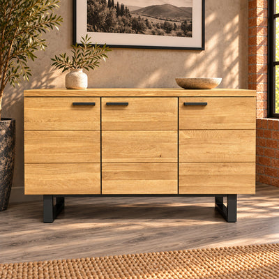 Front view of the Fusion oak sideboard with three grooved cupboard doors and charcoal metal handles.
