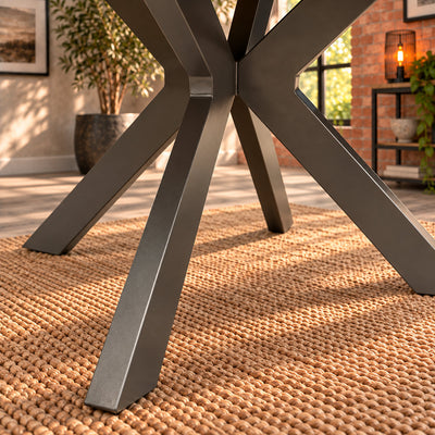 Close-up of the Fusion round dining table's angular metal legs meeting at the central junction.
