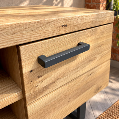 Charcoal rectangular pull handle with squared returns on the Fusion oak TV unit's textured oak cupboard door.
